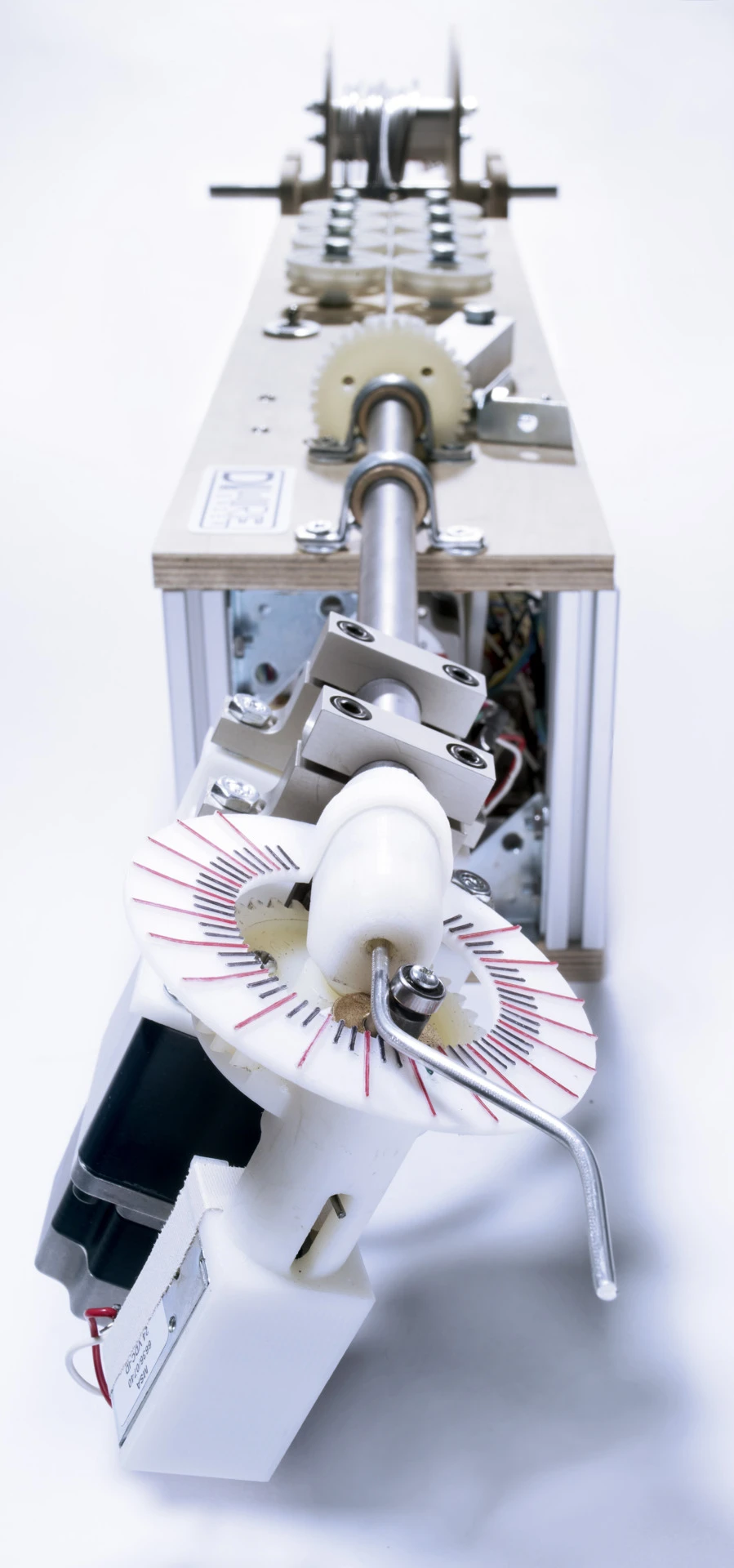 Aluminum wire unspools from one end of the machine, is straightened by several wheels along the length of it, and is finally shaped as it passes through a bending head