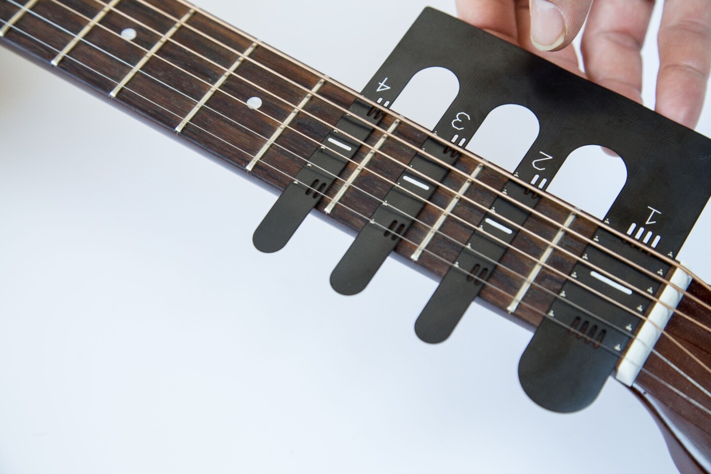 The FretX LED learning sleeve is slotted under the strings at the nut