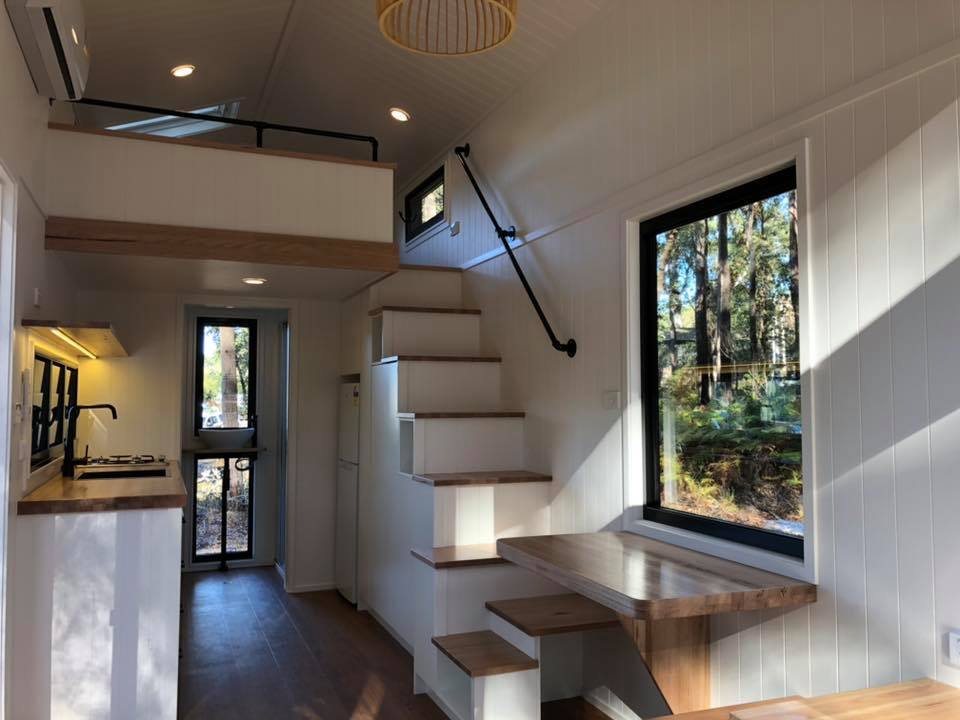 The two-seater dining table is incorporated into the structure of the staircase, a feature not often seen in tiny homes
