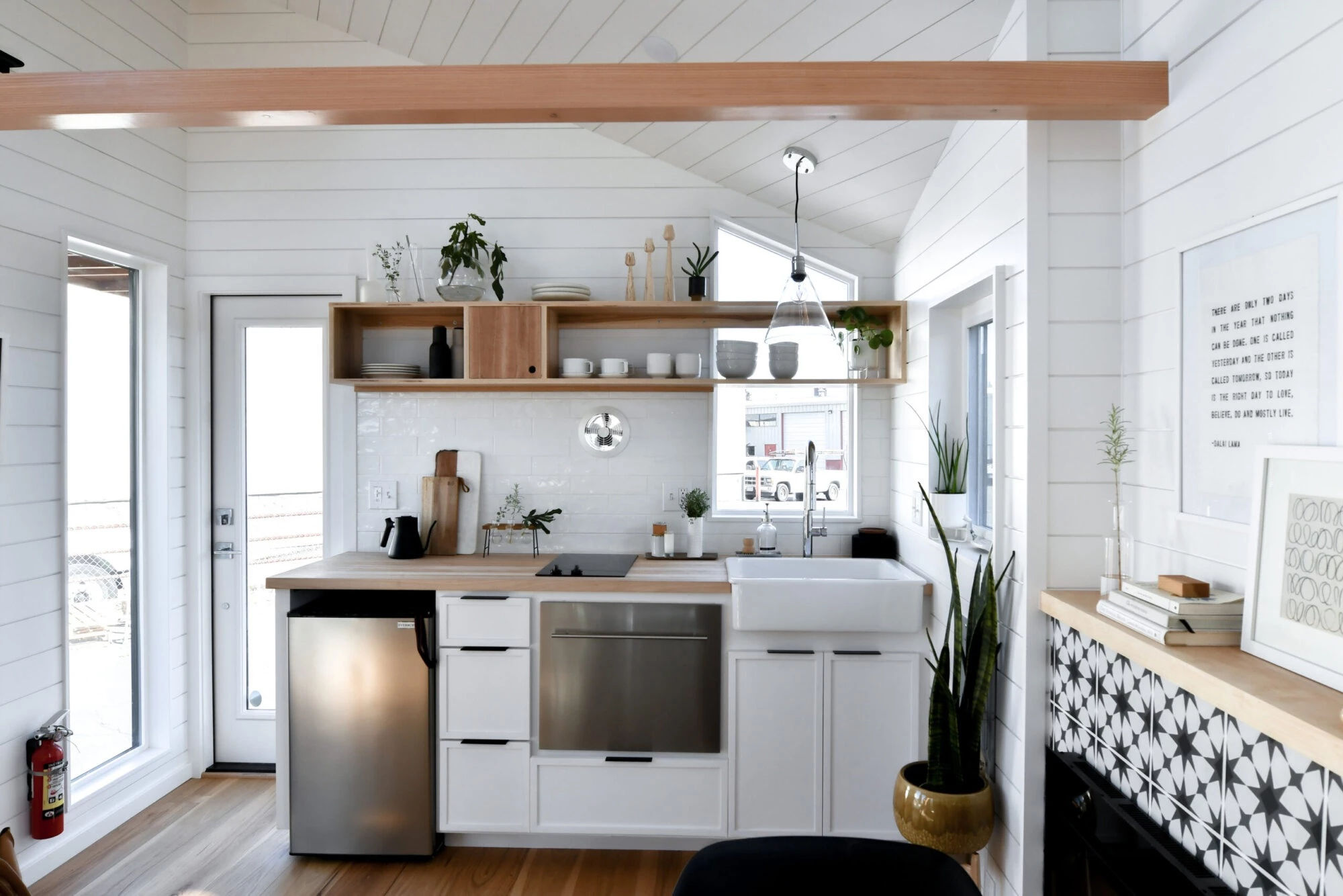 The Urban Park Studio's kitchen is small but includes a fridge/freezer, oven with two-burner electric stove, and farmhouse-style sink