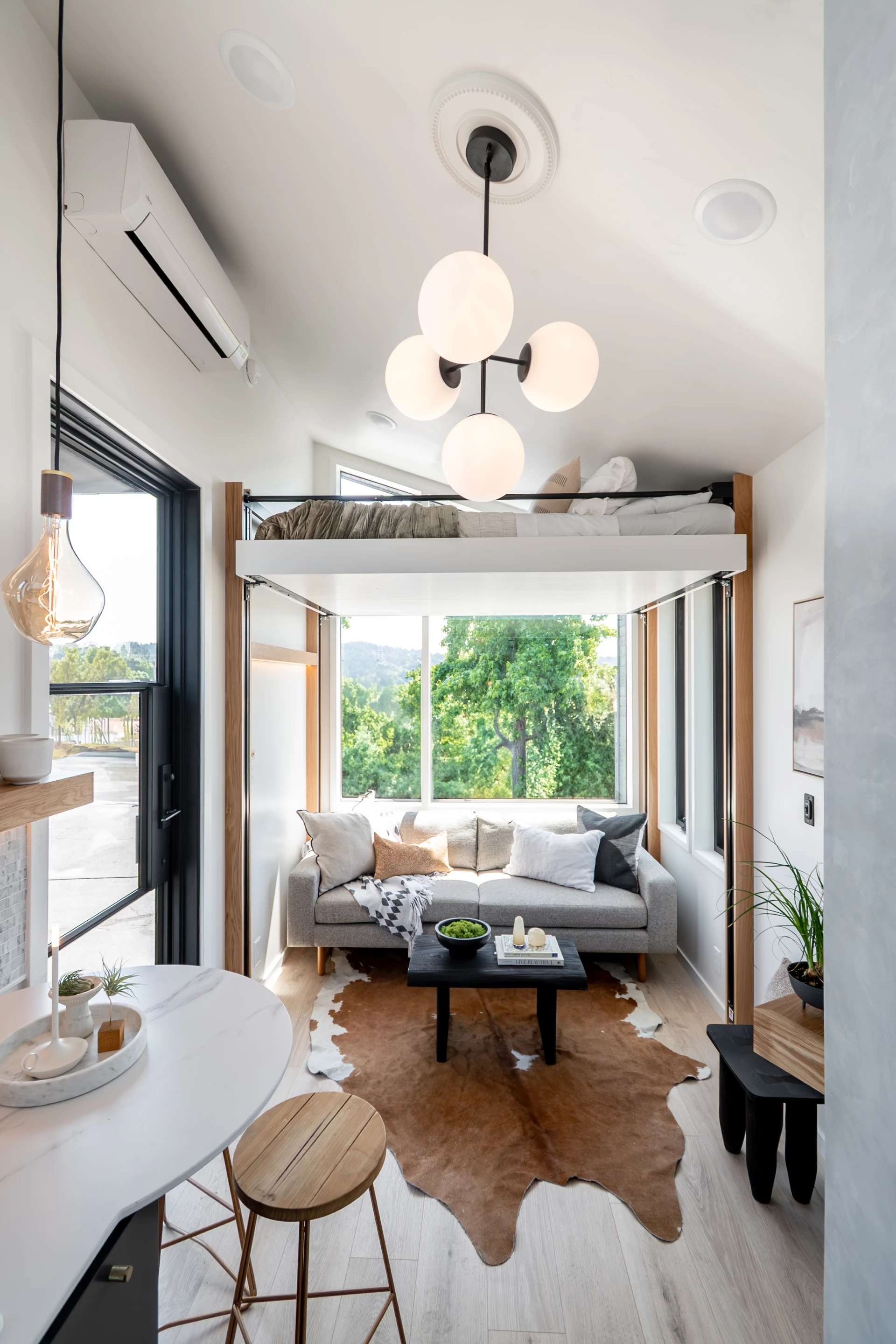 The Terra Urban's living room includes a sofa, with the elevating bed positioned above, near the ceiling