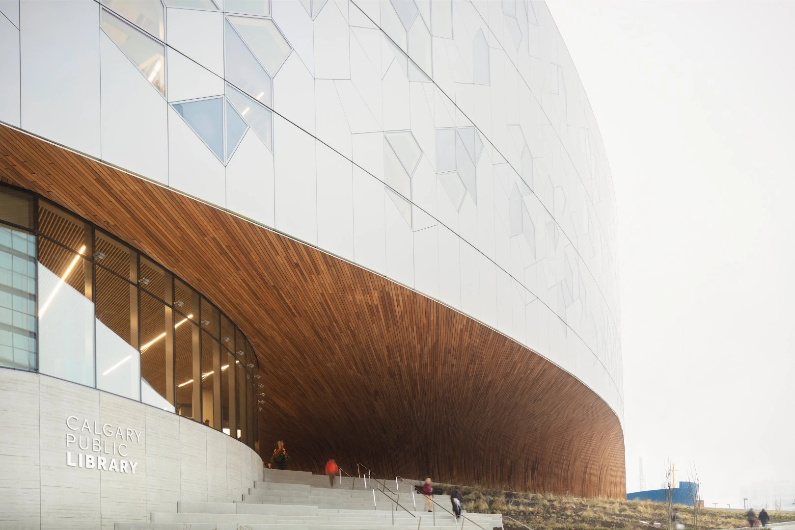 Visitors enter Calgary Central Library through a large wood archway inspired by the Chinook cloud arch