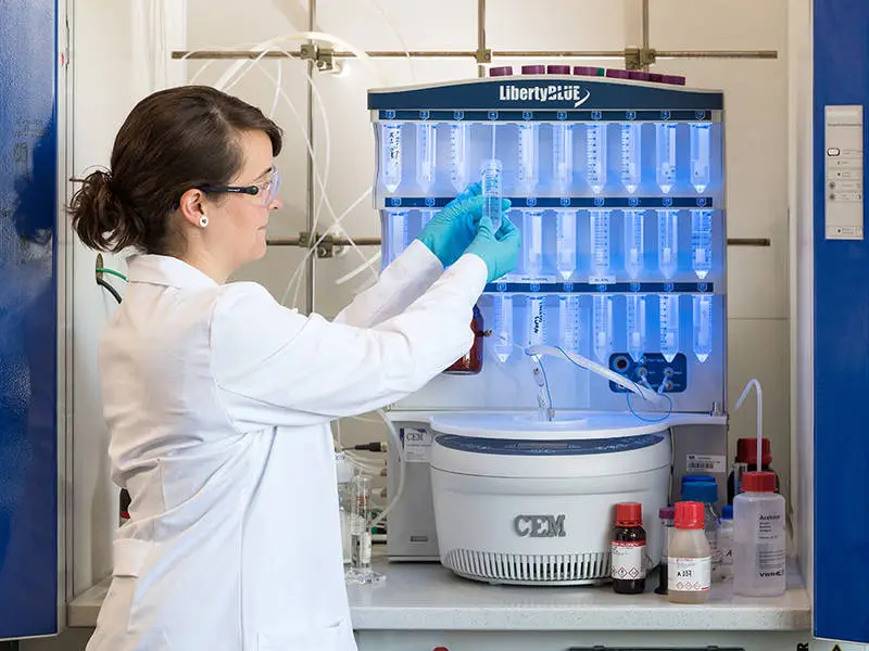 Project researcher Marta Tena-Solsona, with the peptide synthesizer that produces the molecular building blocks of the self-destructing materials