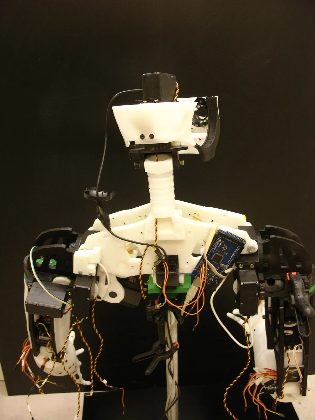 A rear view of InMoov's upper torso reveals a bundle of wires and other electronic components