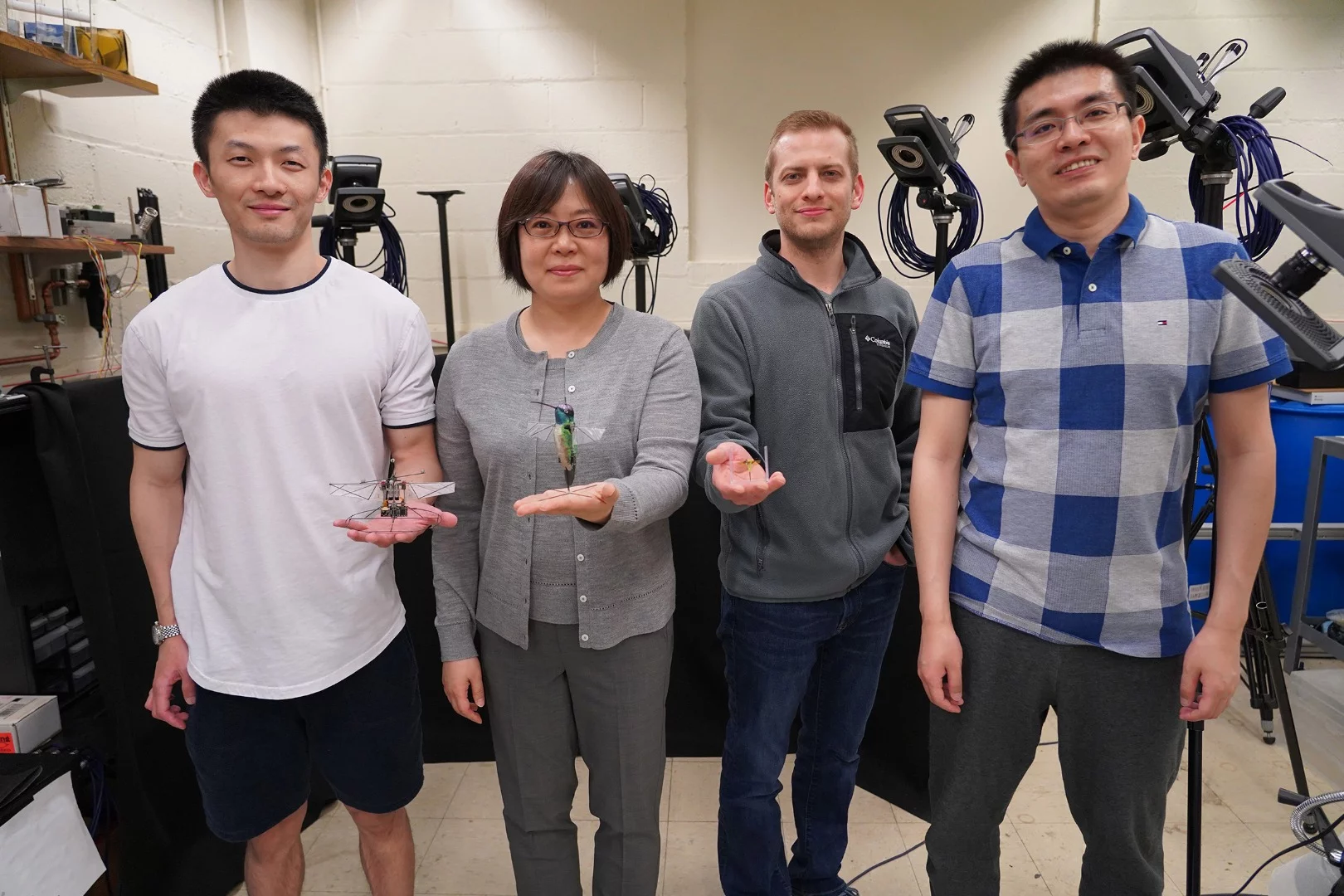 The researchers on the team (from left: Fan Fei, Xinyan Deng, Jesse Roll and Zhan Tu), with the robotic hummingbird and insects
