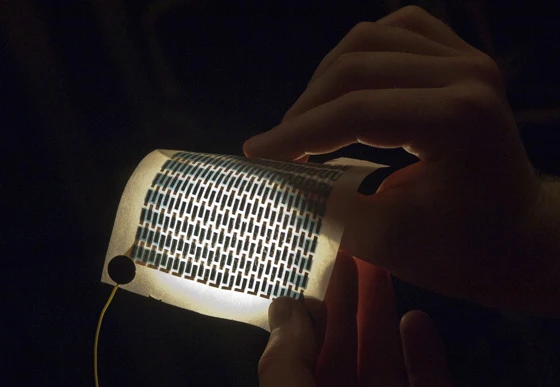 Graduate student Miles Barr holds a flexible and foldable array of solar cells that have been printed on a sheet of paper(Photo: Patrick Gillooly/MIT)