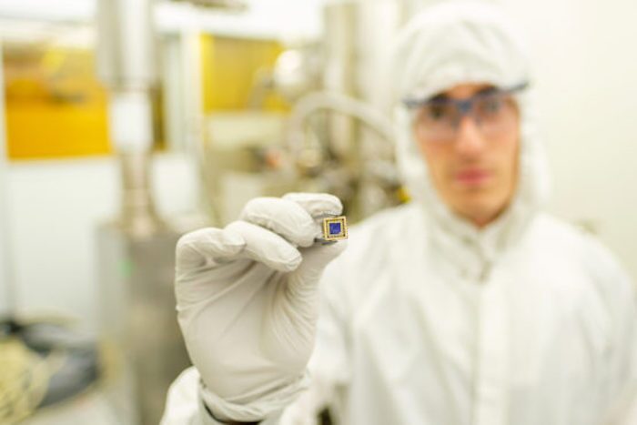 Researcher Aaron Sharpe holding a device made of twisted bilayer graphene