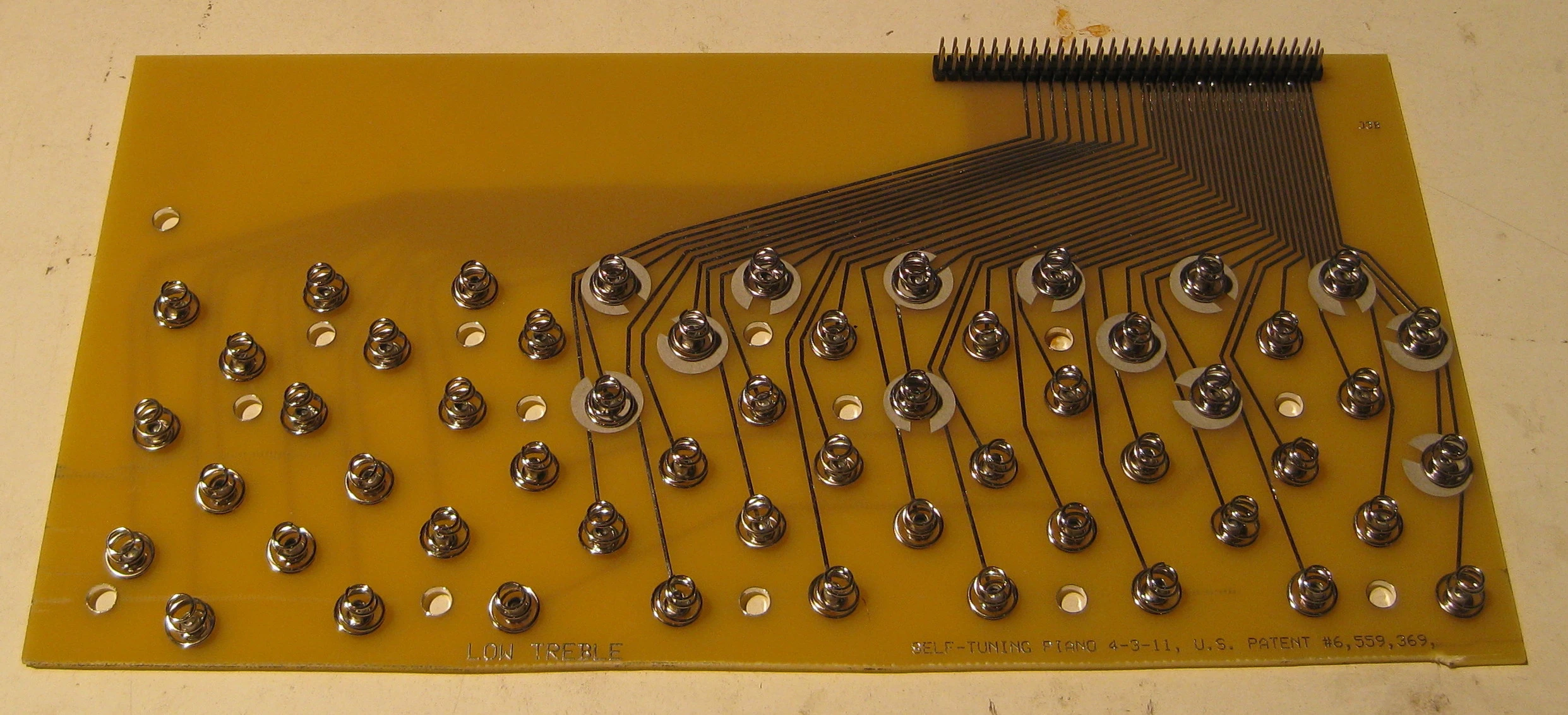 The pitch is adjusted using an electrical current delivered to each string via ordinary battery-compartment springs riveted to printed circuit boards positioned at the bottom of the tuning pins
