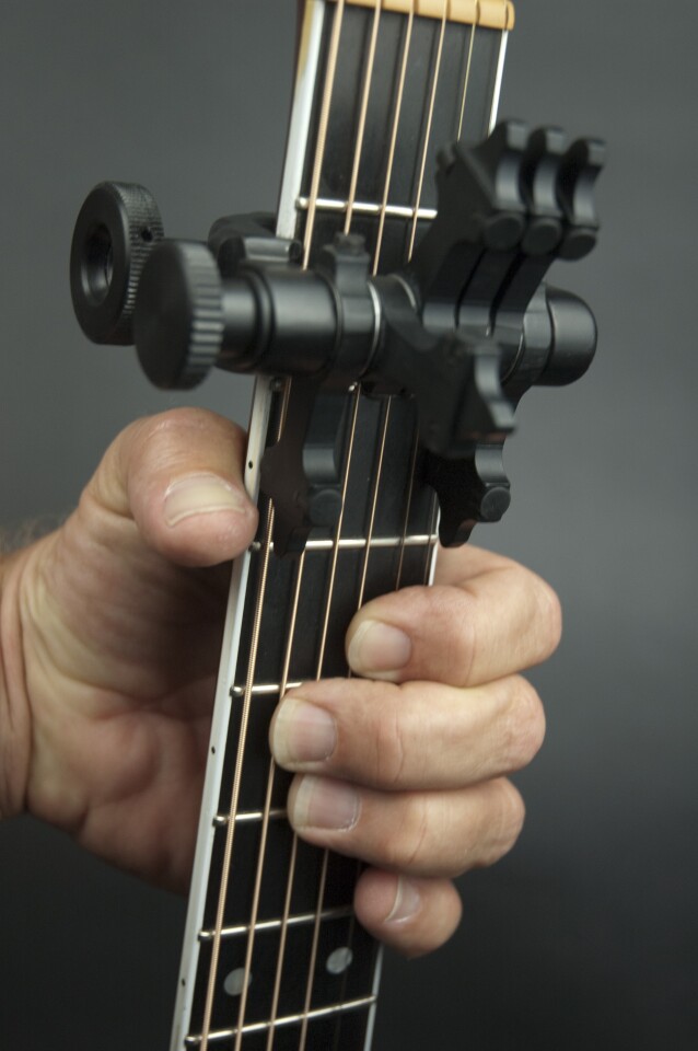 The device can not only hold down notes played directly under the capo, it also uses six individual hammers that can "finger" notes one fret up or down from the capo position