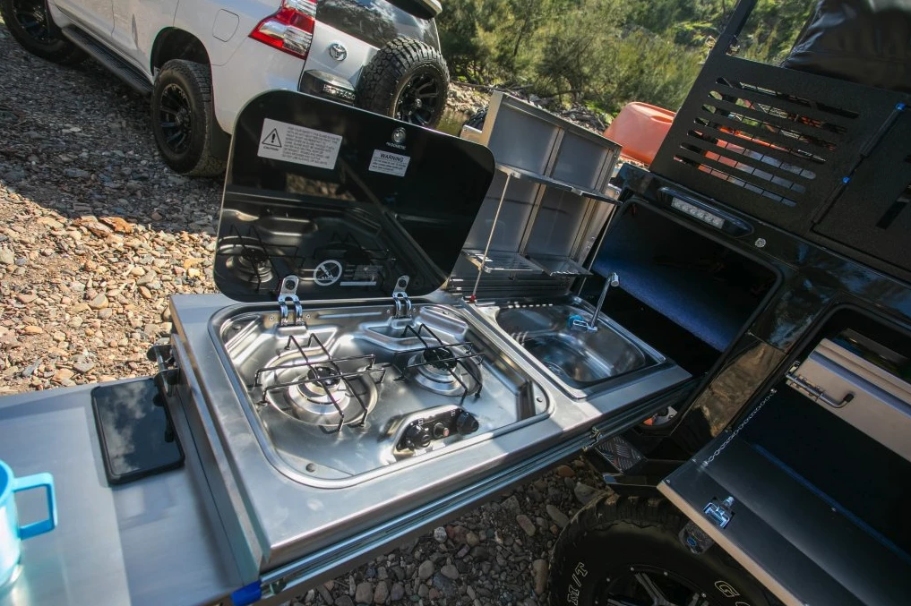 The slide-out kitchen puts a dual-burner Dometic stove, sink with collapsible dish rack and extendable worktop in one place