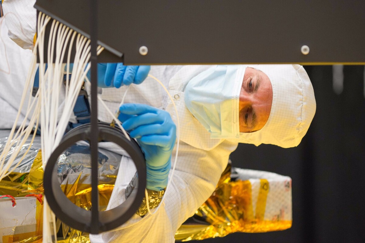 Close-up of Ball Aerospace optical engineer Larkin Carey connecting fiber optics to the AOS Source Plate Assembly
