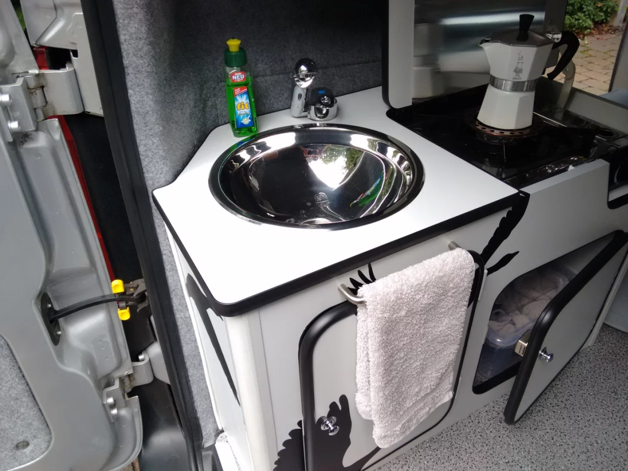 The Flexcamper kitchen includes a sink and single-burner stove