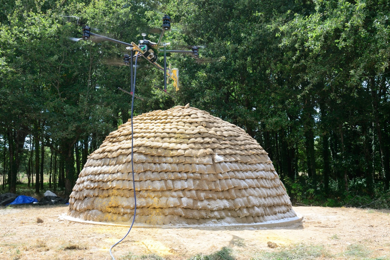A drone applies the exterior finishing to dome shelter