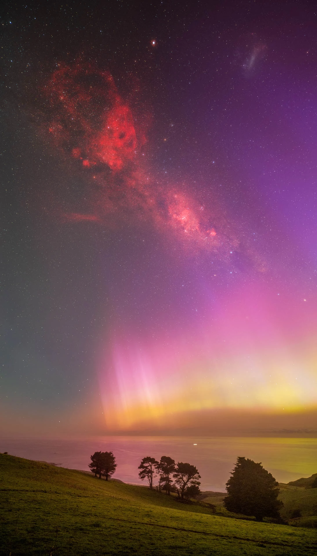Aurora Flame by Richard Zheng, taken on the Dunedin Peninsula, New Zealand. The aurora itself shares the sky with a blood-red nebula in this eerie image