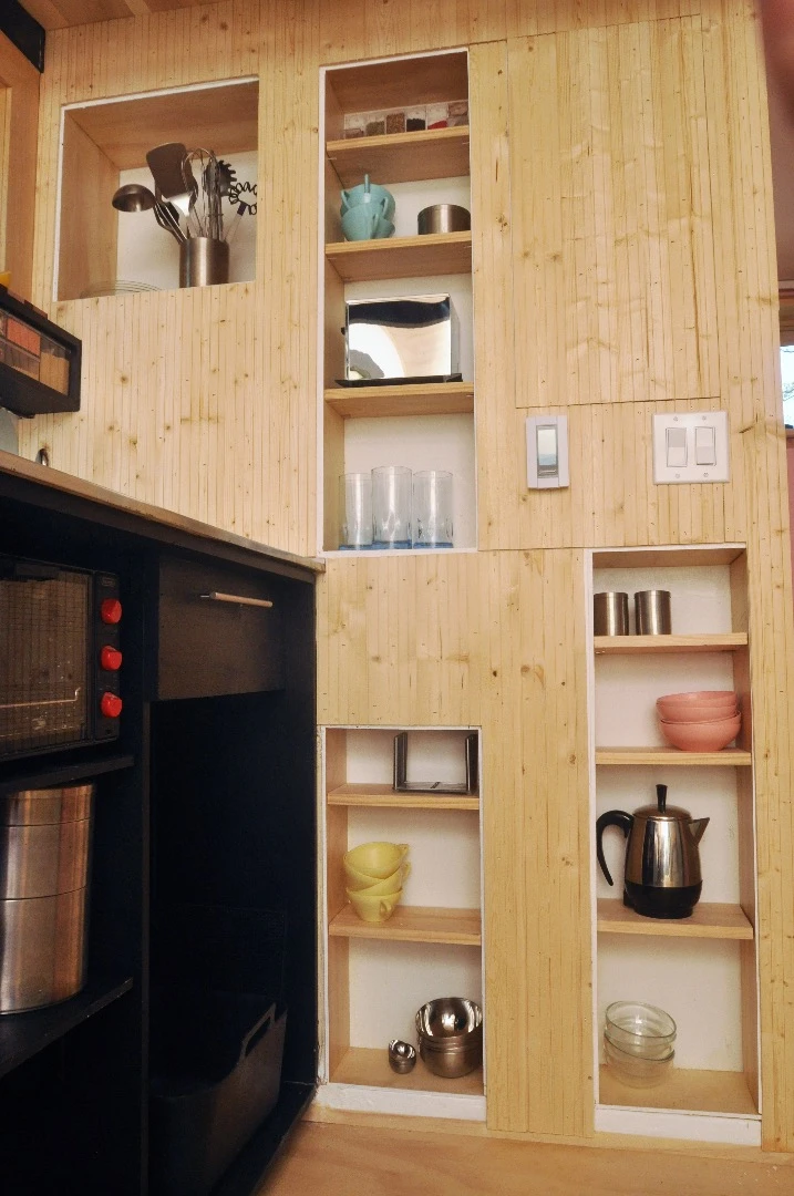 The kitchen features a low-flow faucet and plenty of worktop space, and also includes fridge, freezer, microwave, and a hidden pantry wall