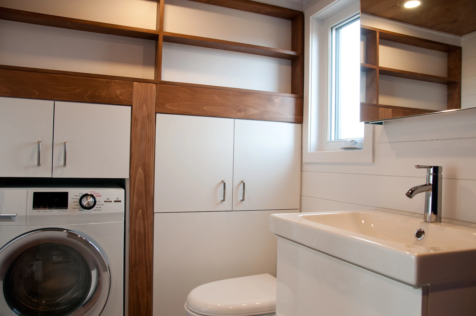 The Charme V2's bathroom includes a flushing toilet, vanity sink, bathtub, and a washer/dryer, as well as some storage space