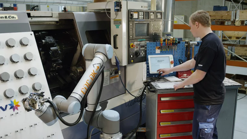 A worker stands alongside Universal Robots' factory robot arm without the need for safety barriers