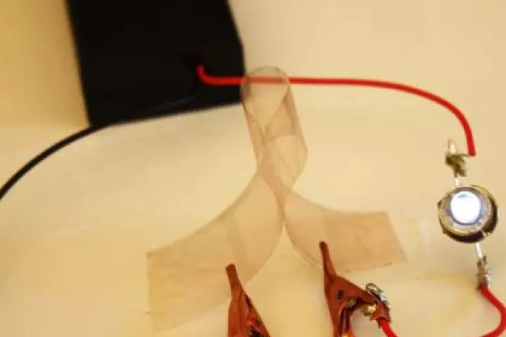 A new flexible film made of copper nanowires and plastic conducts electricity illuminating a small light bulb (Image: Ben Wiley, Duke University)