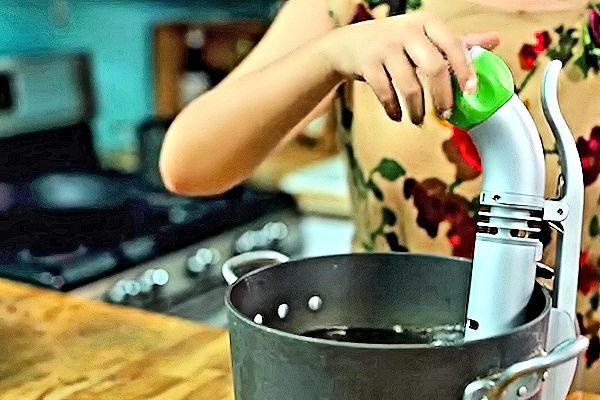 The Nomiku sous-vide immersion circulator in use clamped to the side of a pot