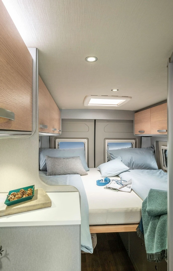 The single beds of the 602 floor plan are installed longitudinally so sleepers can access the bathroom and front of the van without climbing over each other