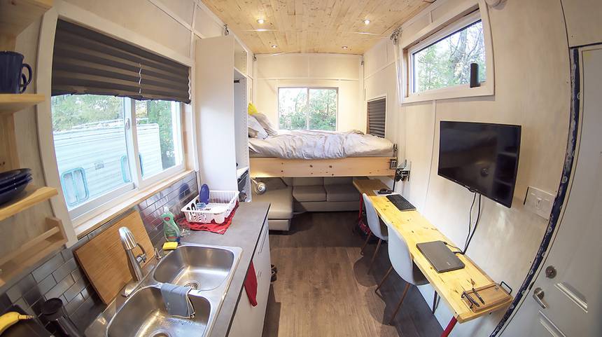 The tiny home consists of a cozy living area, desk area with computer station and European style wall kitchen