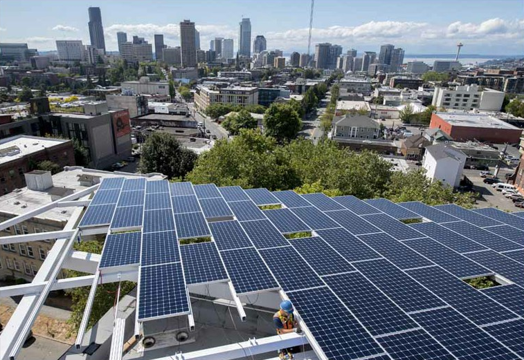 A view of the Seattle skyline from the roof of the Bullitt Center as a workman lays cable for the rooftop solar array, August 2012 (Photo: John Stamets)
