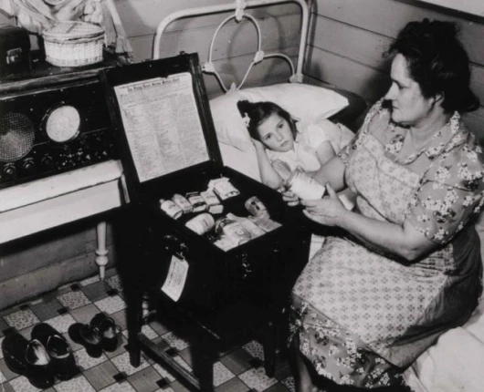 A mother consults the medical chest after an on-air consultation in the 1930s