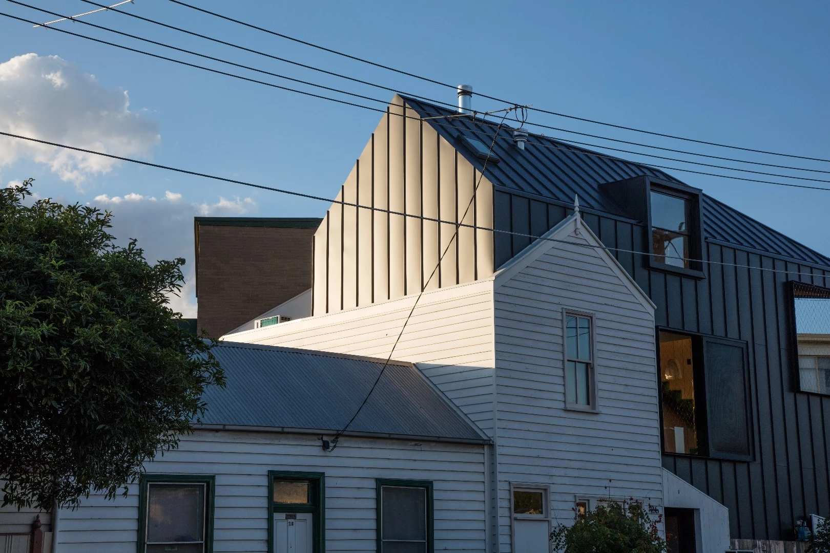 The Acute House is clad in matt black aluminum and salvaged timber from the previous house