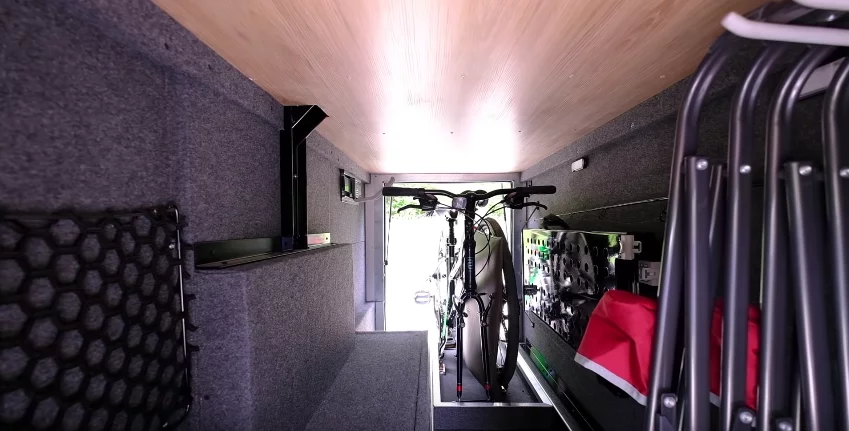 A look inside the pass-through garage with two bikes, chairs and other gear stored