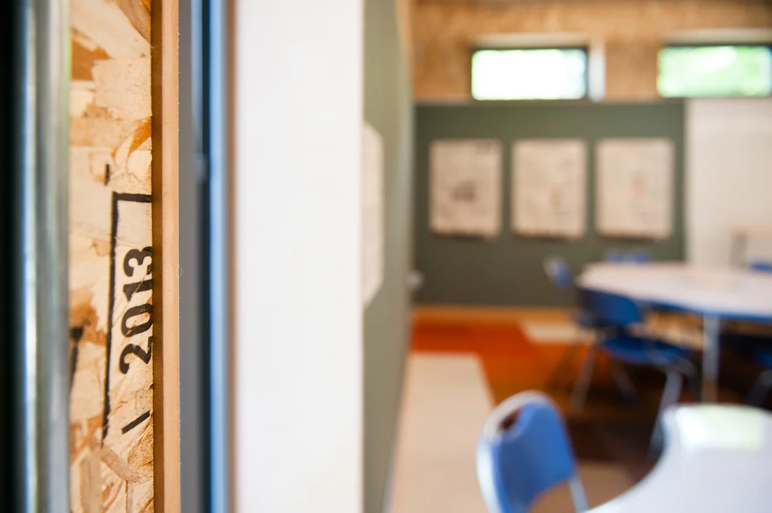 Inside, the classroom looks almost unfinished. The chipboard walls are visible, as are all the ducts, cables, conduits and structural supports, allowing the children to see firsthand how the building works