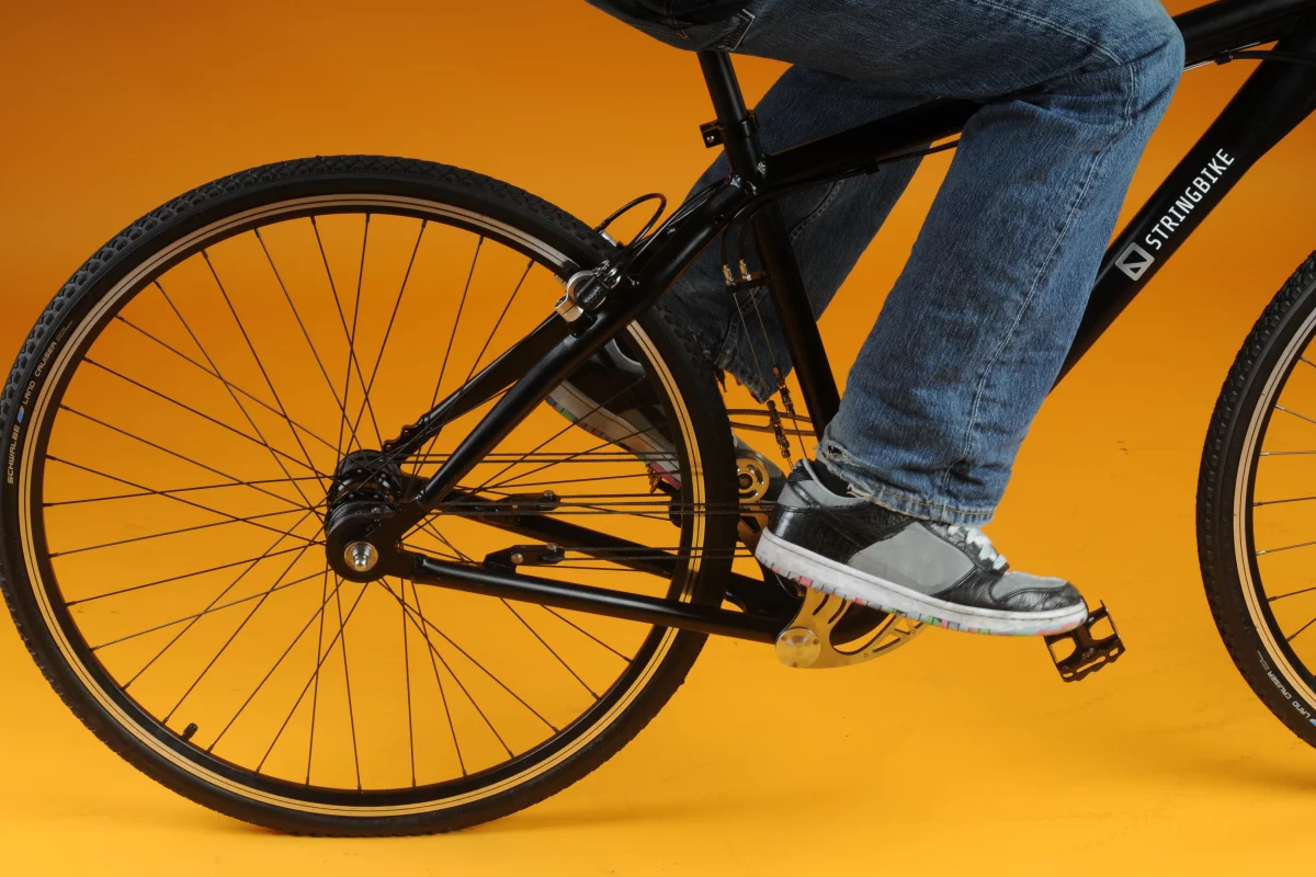 When force is applied to the pedal, the stainless steel, triangular-shaped swinging mechanism pulls on the rope and rotates a drum on the rear wheel to give forward momentum