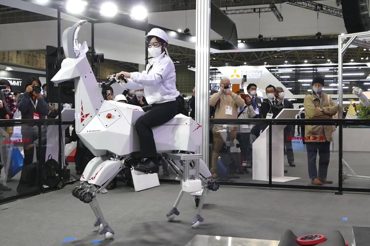 A Kawasaki team member rides "BEX," the robot quadruped, at iREX 2022