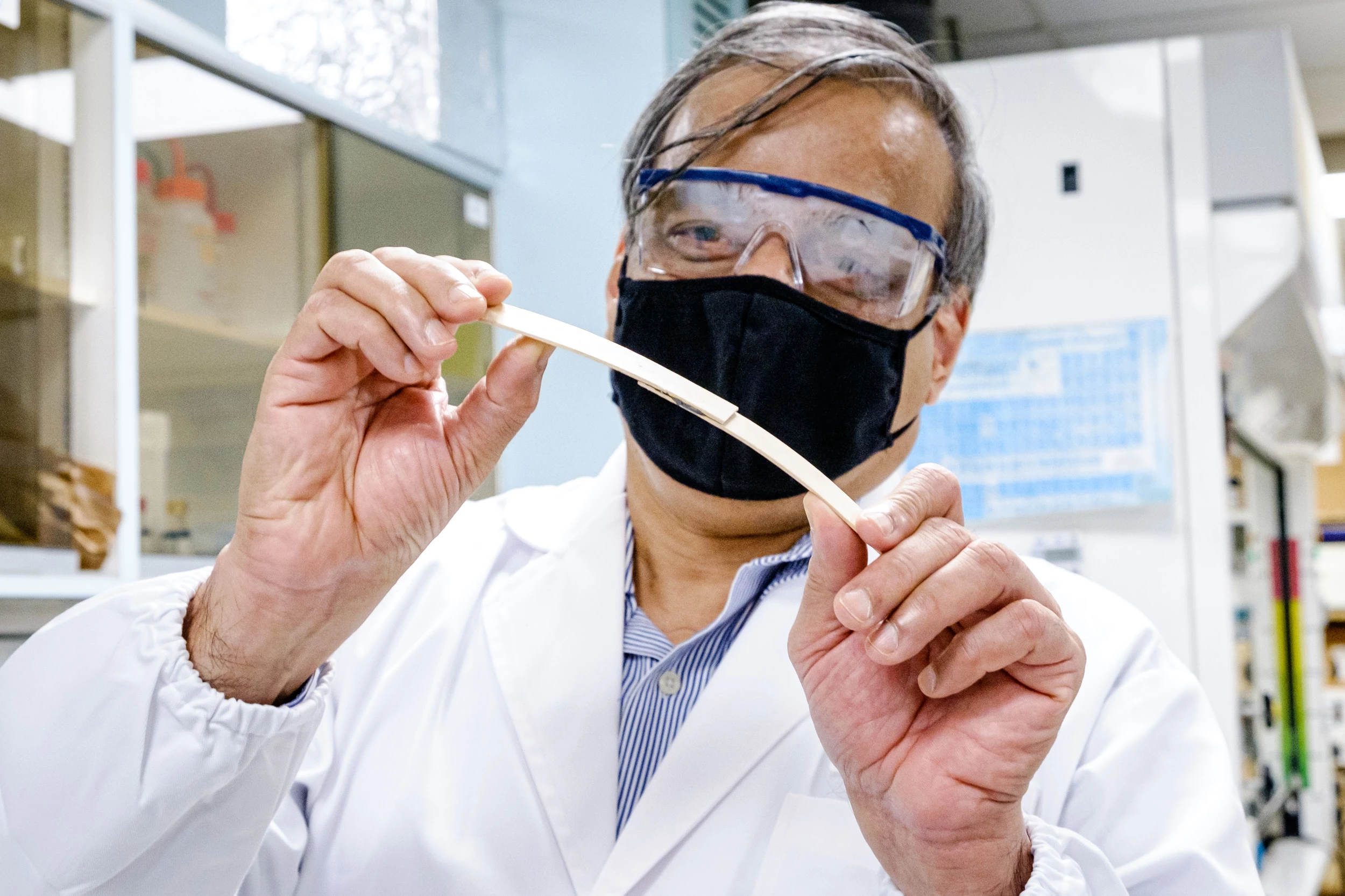 Prof. Raju V. Ramanujan holds and bends two pieces of wood, bonded in the middle by the magnetocuring adhesive