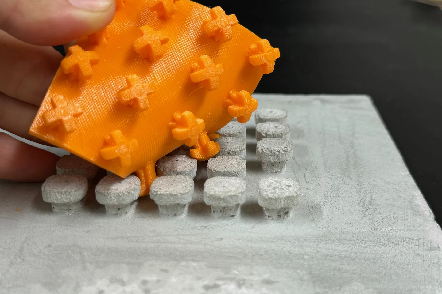 In this particular prototype version of the system, rows of cast-concrete hooks engage rows of 3D-printed loops that are attached to the edges of replaceable interior wall panels