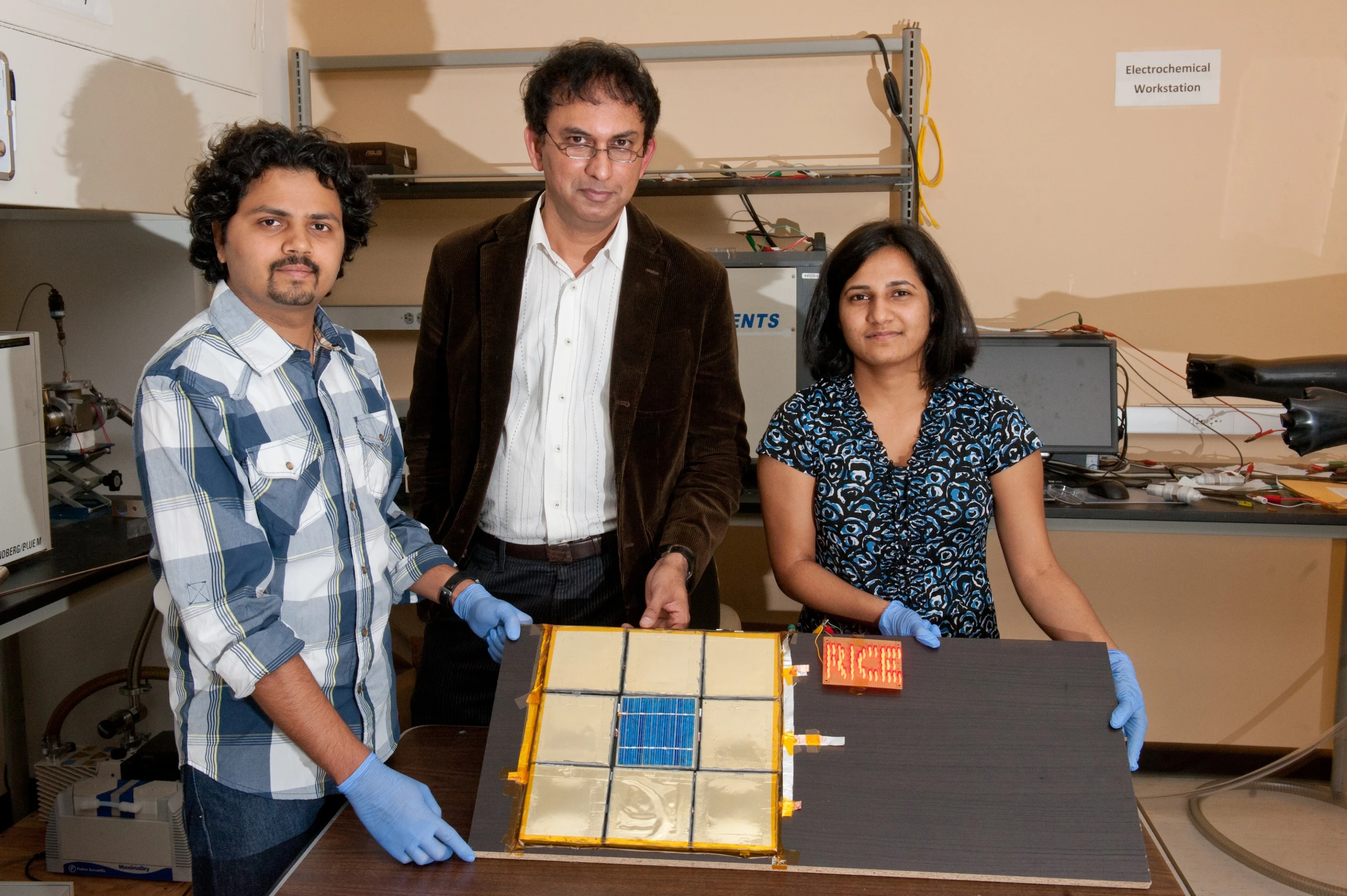 Rice University graduate student Charudatta Galande, Professor Pulickel Ajayan and graduate student Neelam Singh show off the first test device for their paintable batteries (Photo: Jeff Fitlow/Rice University)