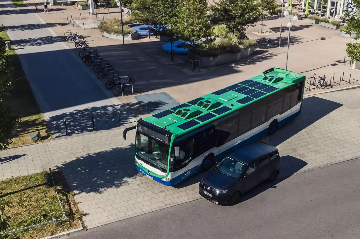 A diesel bus fitted out with Sono Solar Technology parked next to the Sion solar electric vehicle