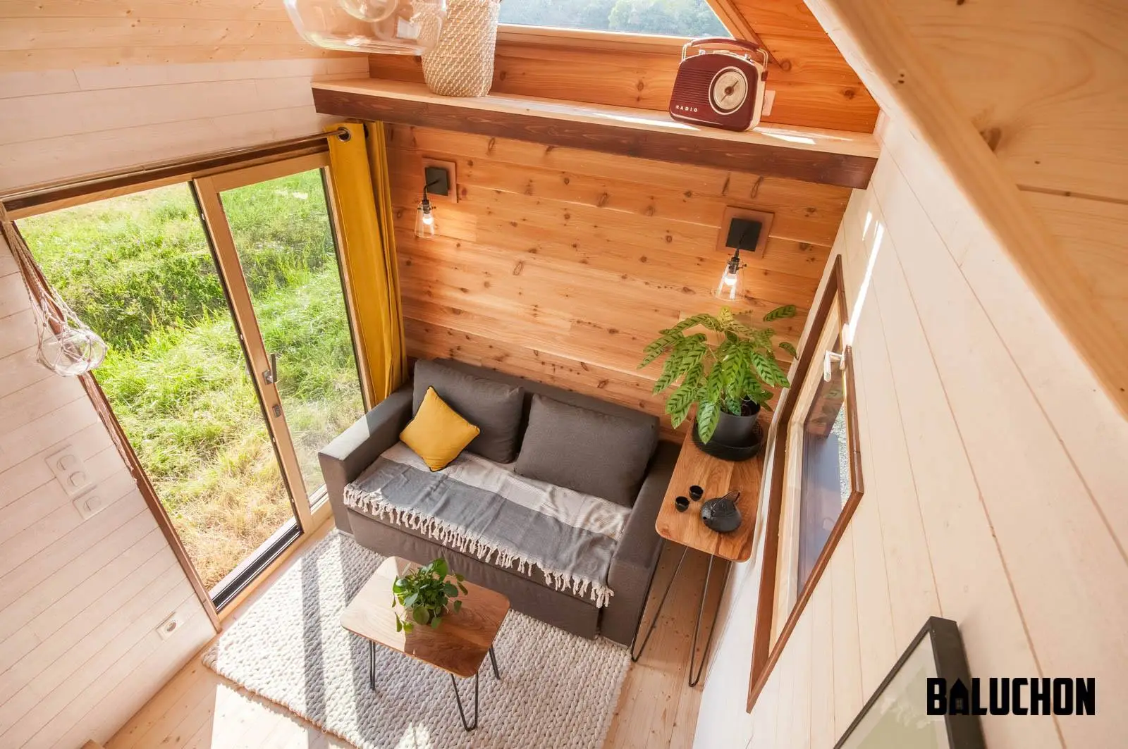 Visitors enter the Pampille into a living room with sofa bed, coffee table, side table, and small storage loft