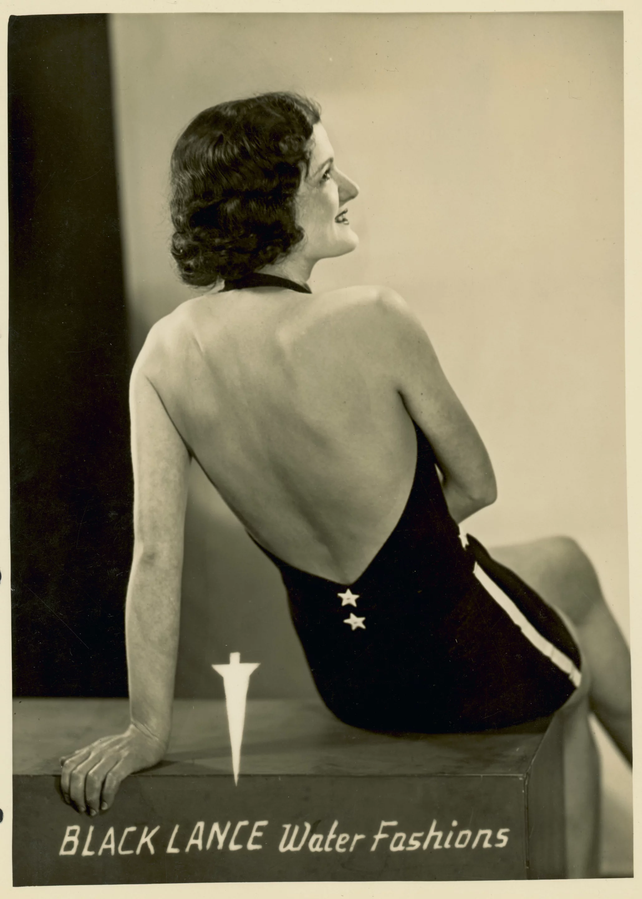 Black Lance's popular 'Brigadier' style swimsuit featuring a backless halter attached to skirt with inbuilt trunks. This swimsuit reflects the 1930s trend for revealing more of the body and strap free tanning. Black Lance Water Fashions was an Australian label established in 1931