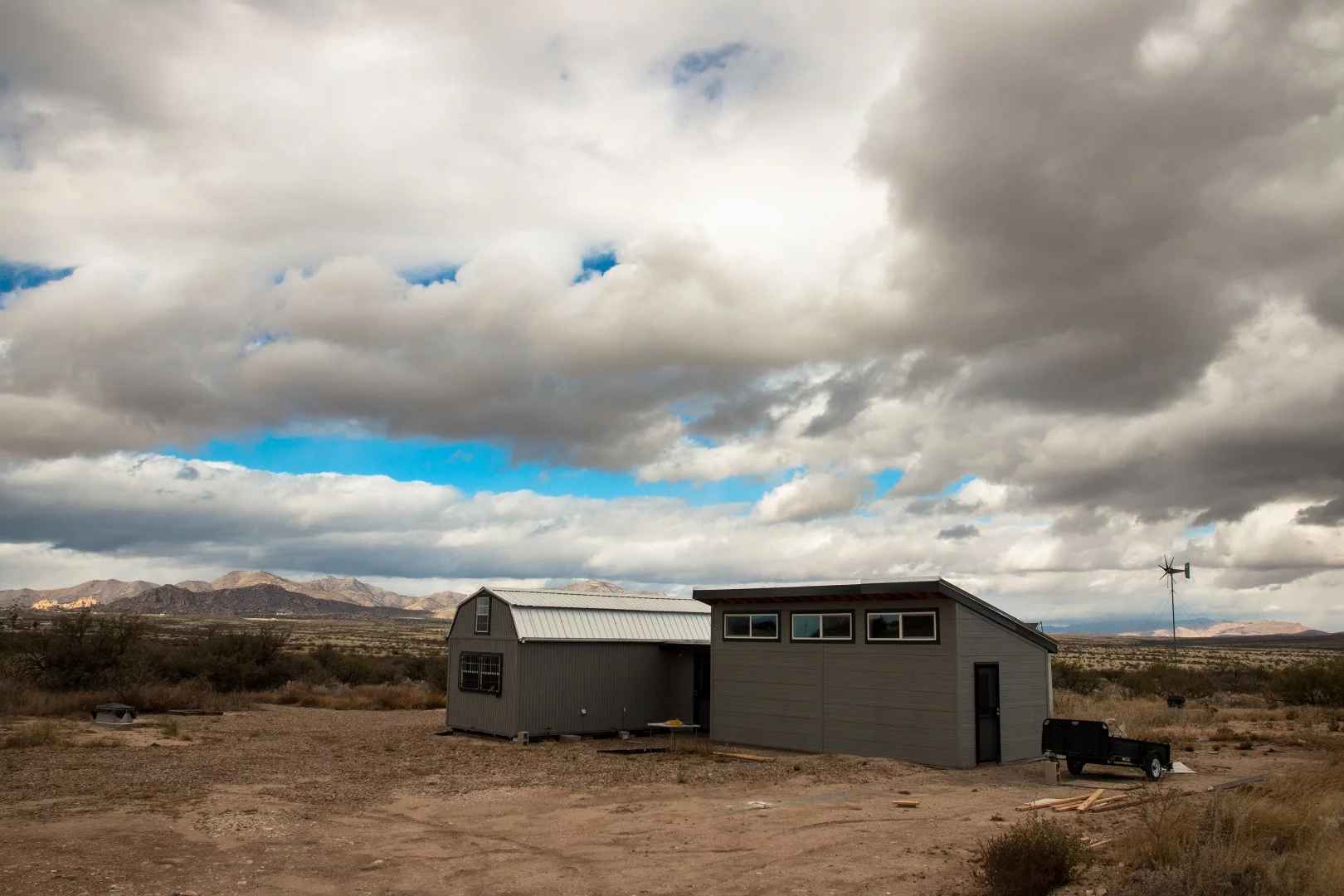The building on the left is the original 340sq ft barn. The building on the right is the addition Chris is currently building. It adds an additional 300sq ft. Behind, you can see the wind turbine.