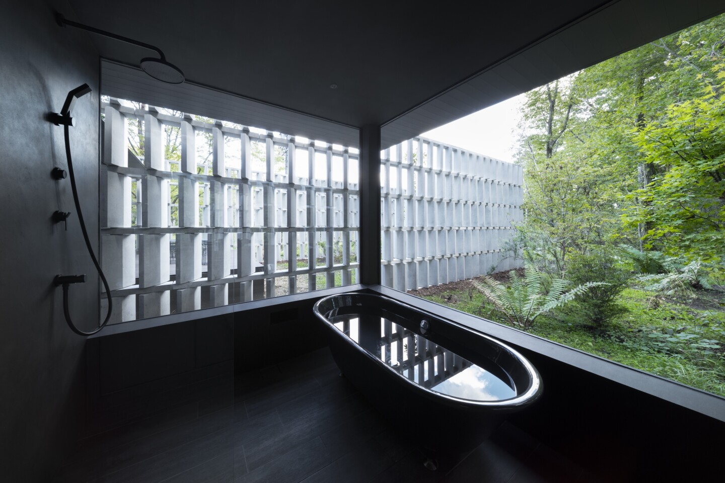 The Block-Wall House's interior decor is very minimalist and dark, putting the focus on the lush greenery outside