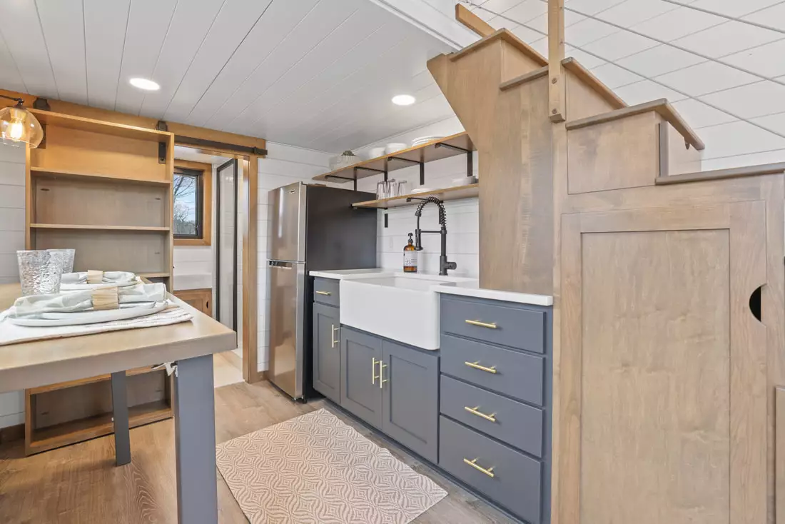 The Coastal Modern's kitchen includes a fridge/freezer, farmhouse-style sink and a dining table/desk