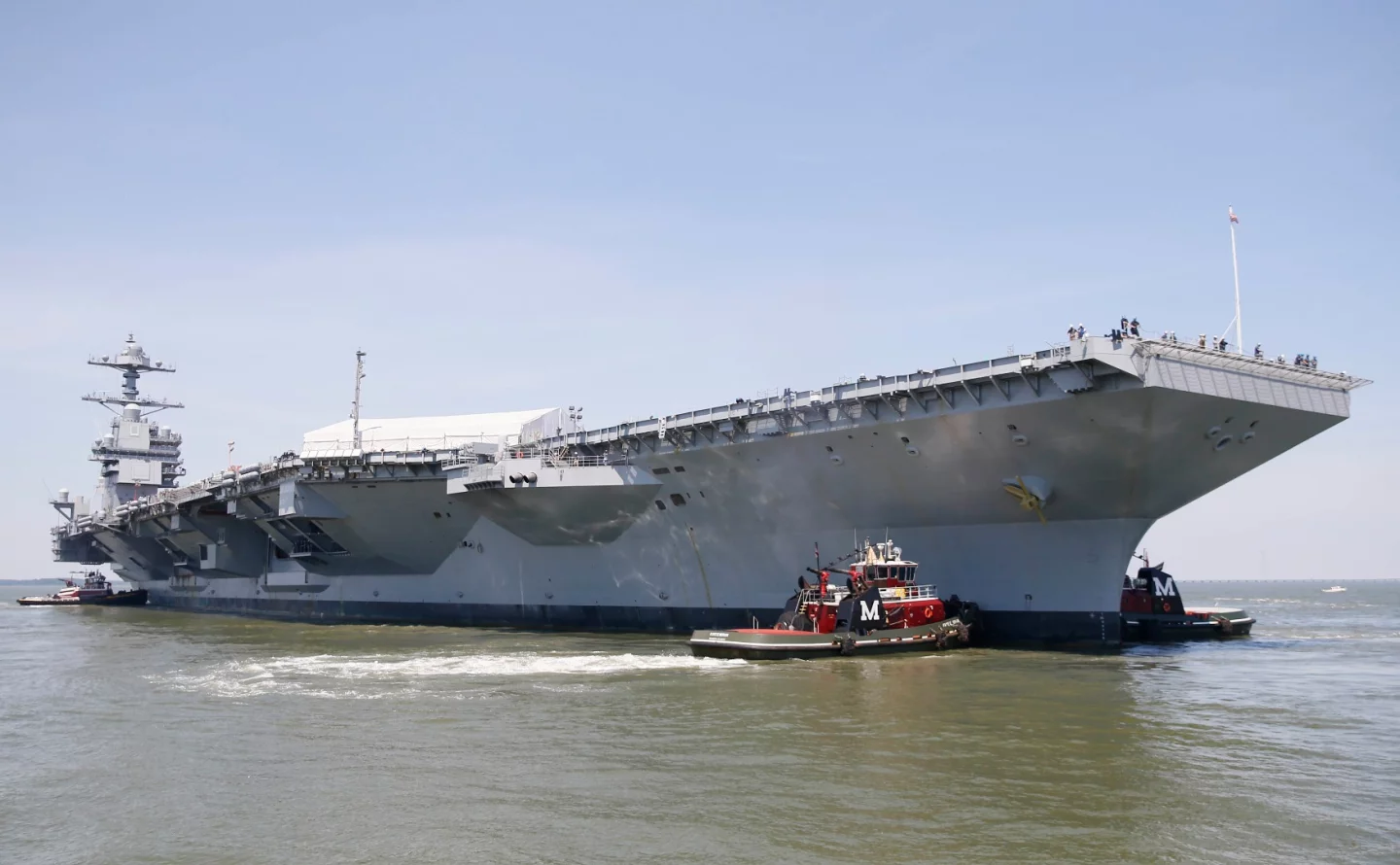 Tug boats maneuver the aircraft carrier Pre-Commissioning Unit Gerald R. Ford (CVN 78) into the James River during the ship's turn ship evolution