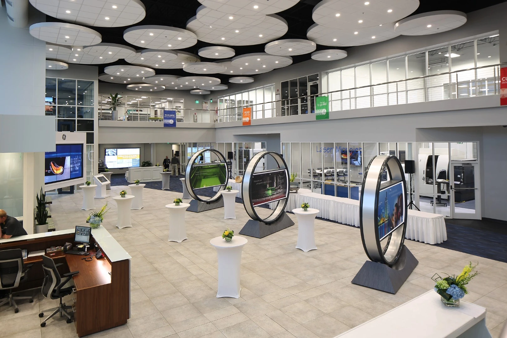 The futuristic, minimalist, lobby of the new facility features TV screens set in circles, while a wall of glass shows engineers busy on cutting-edge projects