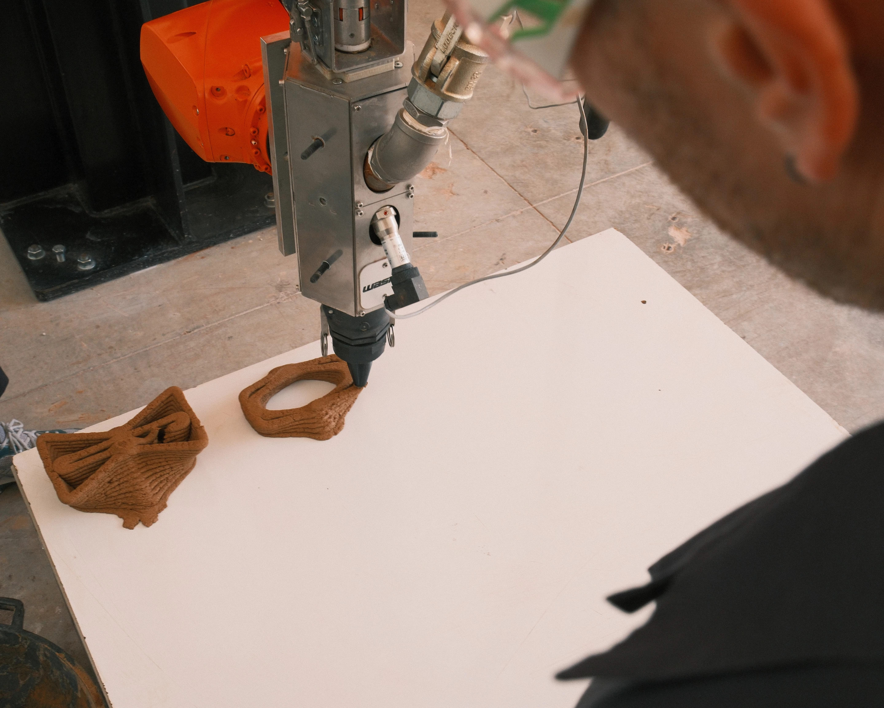 Components are fabricated using a KUKA KR50 robotic arm paired with a WASP LDM XXL extrusion system