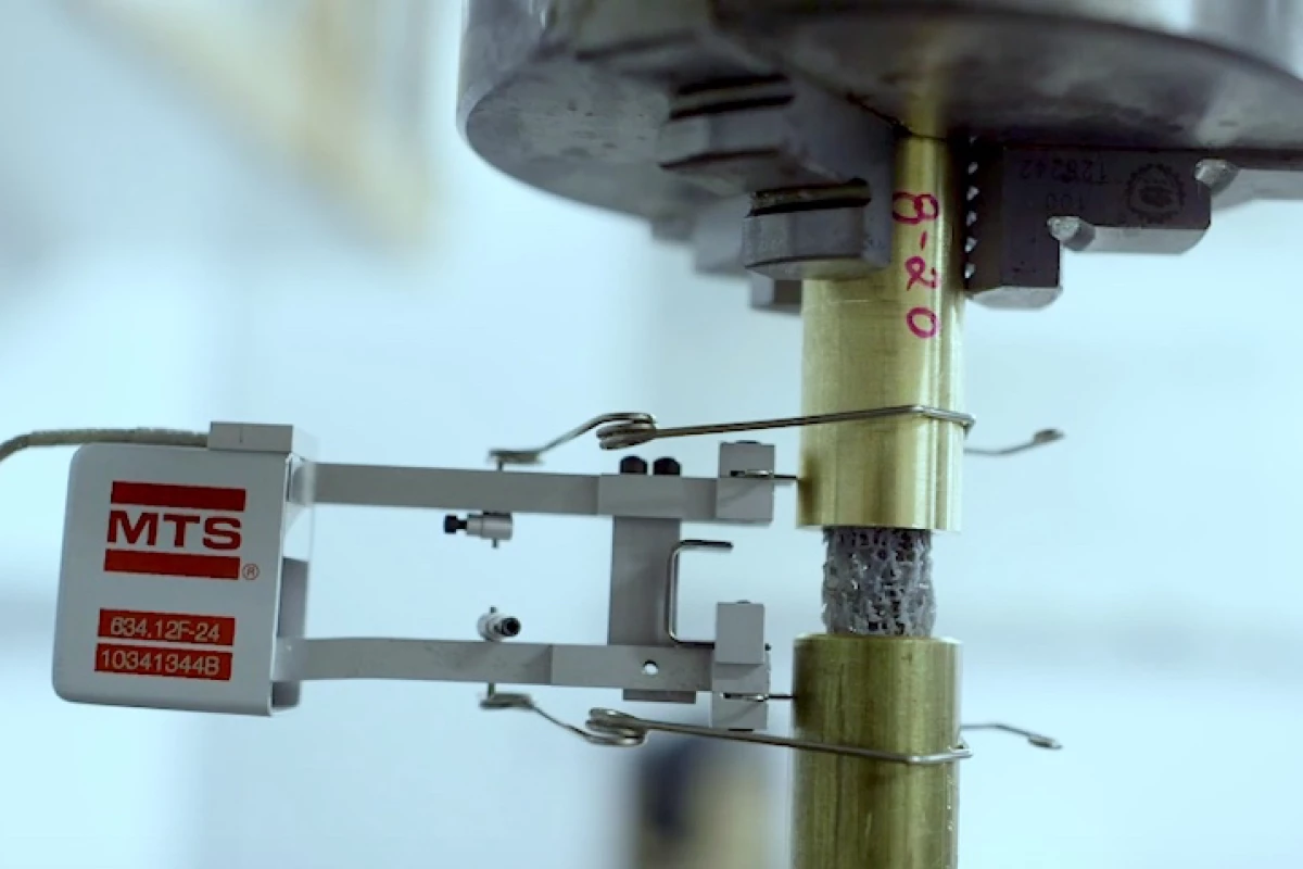 A piece of 3D-printed bone-like material (gray) is subjected to cyclic load testing