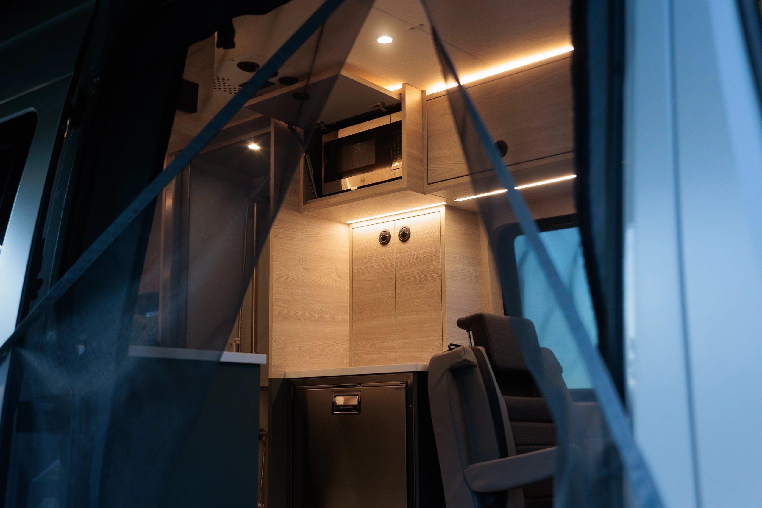 Opening the side mosquito screen to see the fridge and microwave across from the main kitchen block