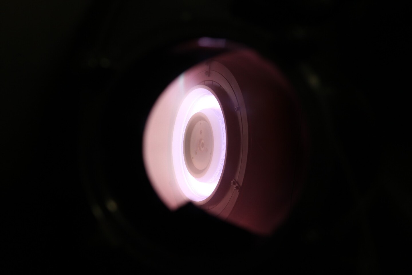 The purple color of the engine plume is attributed to the fact that the thruster is running on air molecules