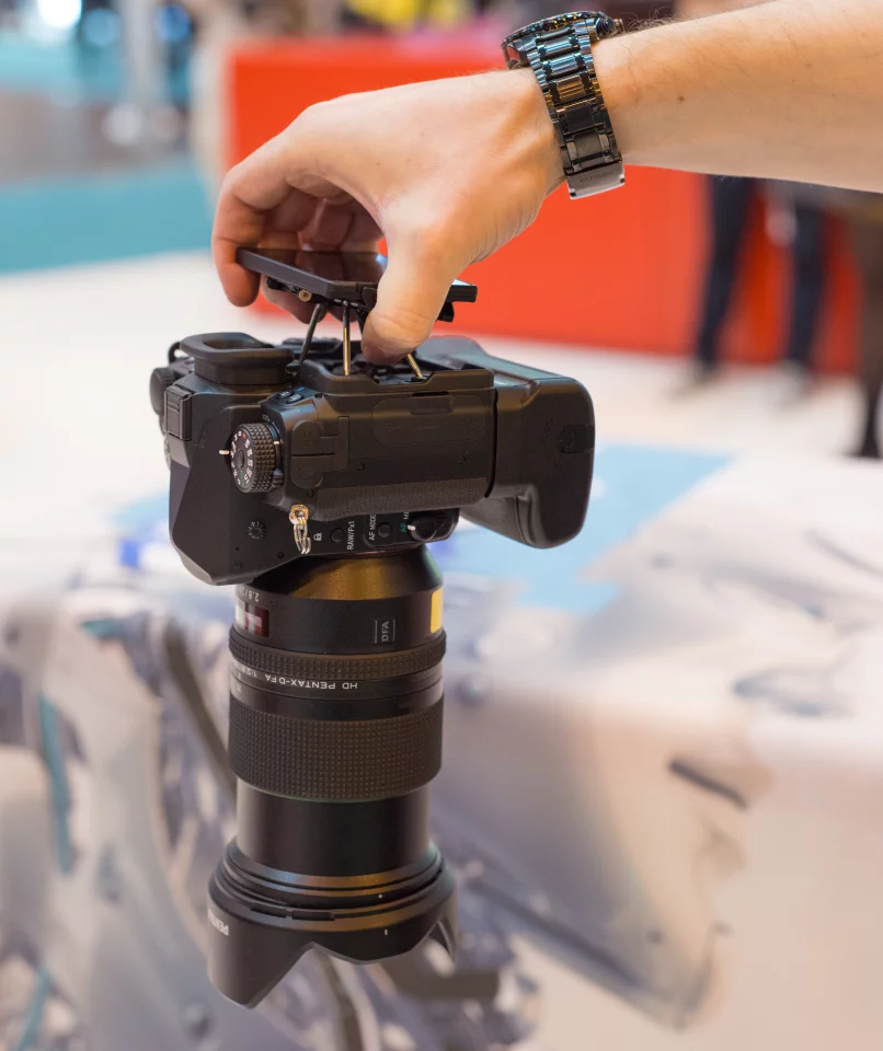 A Pentax representative shakes the Pentax K-1 (with a battery-grip and 24-70 F2.8 lens) by the rear monitor