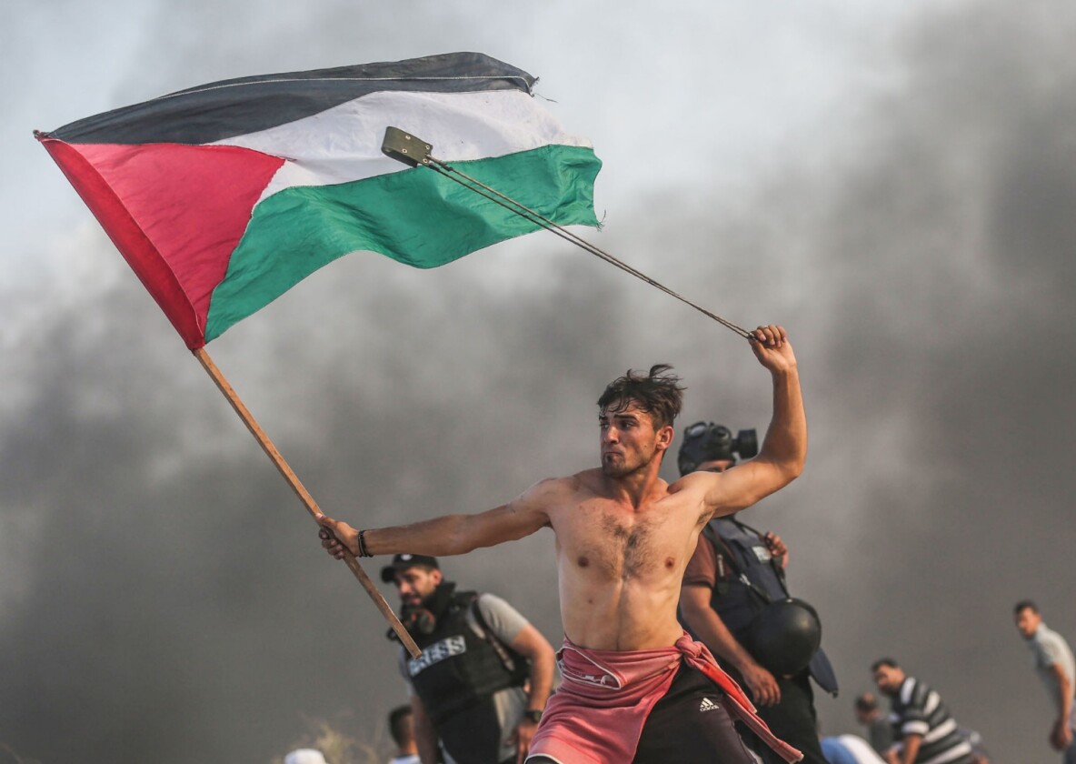 Professional shortlist: A shirtless young protester in Gaza gripping a Palestinian flag with one hand and swinging a slingshot over his head with the other