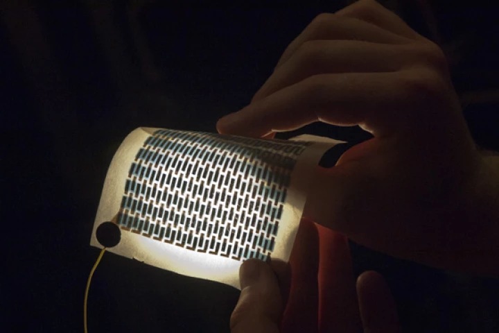 Graduate student Miles Barr holds a flexible and foldable array of solar cells that have been printed on a sheet of paper(Photo: Patrick Gillooly/MIT)